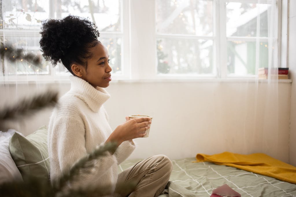 Young woman enjoying a warm drink on a cozy morning indoors.