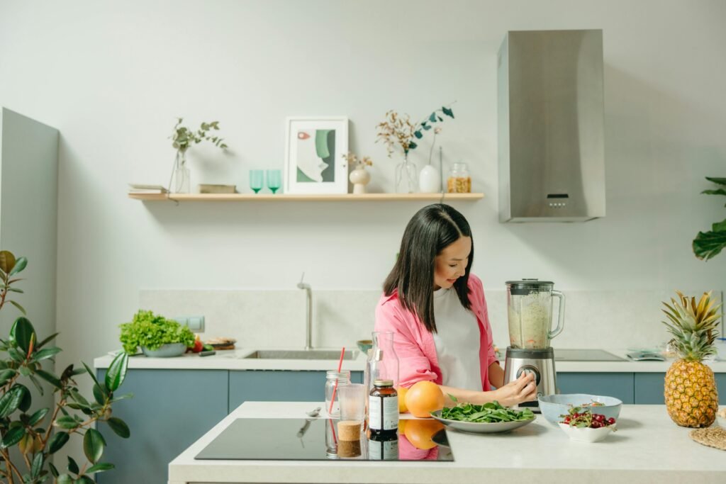 A woman blends fresh ingredients for a healthy smoothie in a stylish kitchen, promoting wellness.